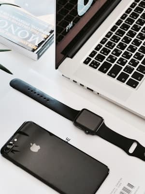 a table with a laptop, smart watch and a mobile phone